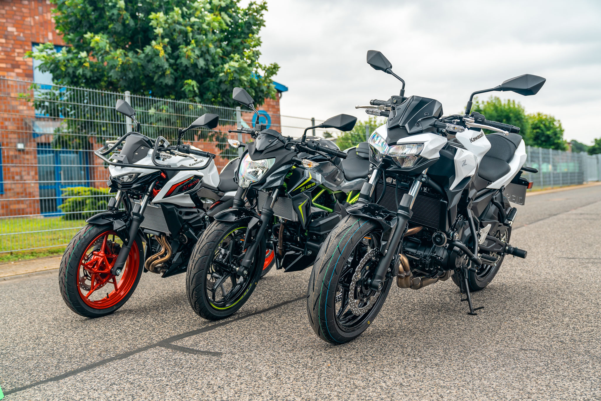 Der moderne Motorrad-Fuhrpark von Julians Fahrschule in Kleve mit den Modellen Kawasaki Z125, Z500 und Z650 startbereit vor der Fahrschule.
